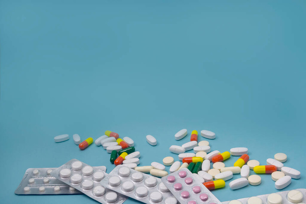 Aspirin and antibiotic pills, vitamins capsules on blue background. Copy space. The concept of health care, protection from the virus and disease. - Foto, Imagem