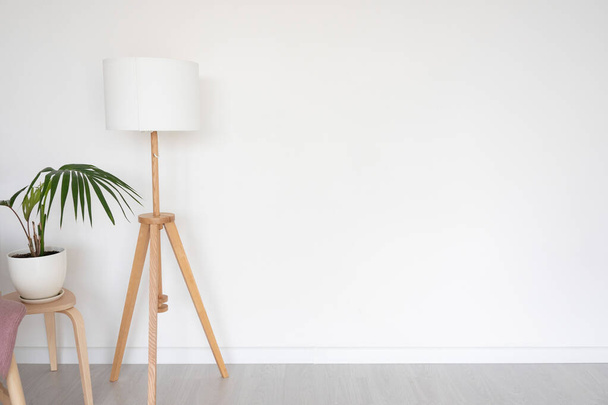 lámpara de pie y taburete con flor interior en el fondo de una pared vacía blanca. espacio para texto. - Foto, imagen