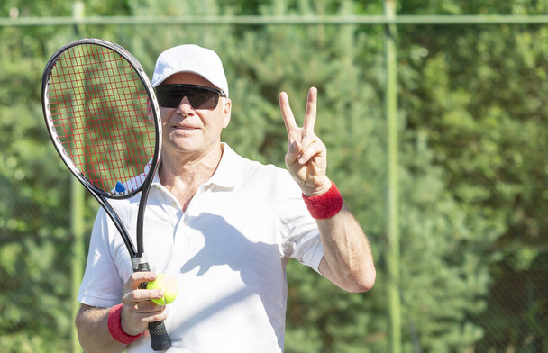 Tenisçi zafer sembolünü eliyle gösteriyor. - Fotoğraf, Görsel