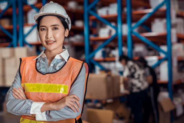 Confident Asian woman owner standing and crossed her arm at goods warehouse store and check for control loading containers box from Cargo freight ship for import and export  - Photo, Image