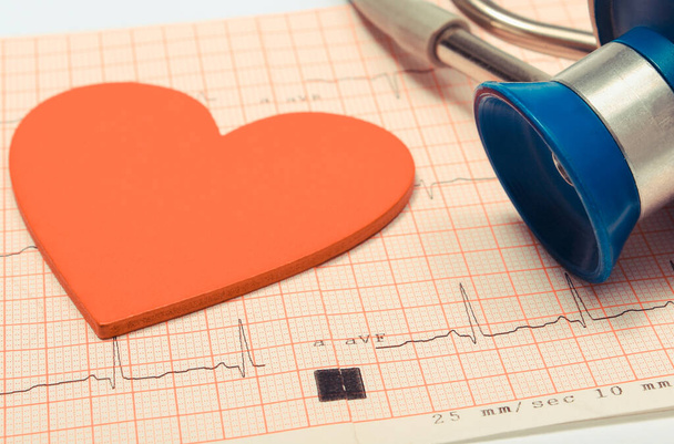 Medical stethoscope and red heart shape lying on electrocardiogram graph report. Ekg heart rhythm. Medicine and healthy lifestyles - Φωτογραφία, εικόνα