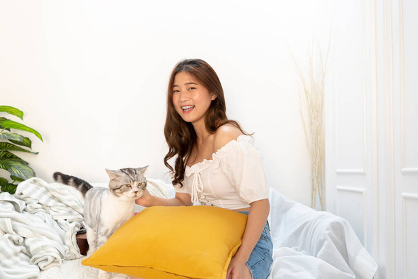 Hermosa mujer tailandesa sexy jugando con el gato en el sofá en la sala de estar. - Foto, imagen