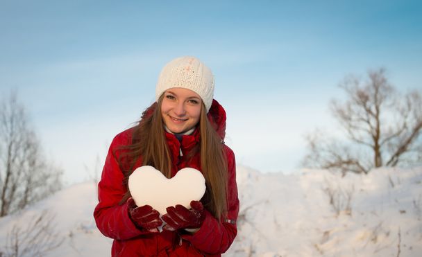 Smiling girl holding a heart of snow. Love. - Fotografie, Obrázek