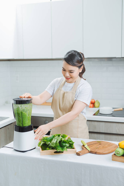 Vihannes smoothie nainen sekoittamalla vihreä smoothies tehosekoittimen kotiin keittiössä - Valokuva, kuva