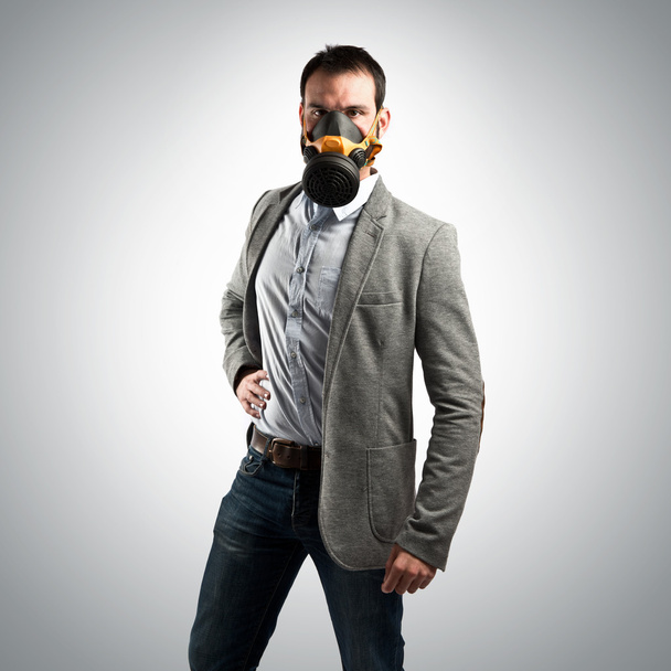 young businessman with gas mask over grey background - Valokuva, kuva