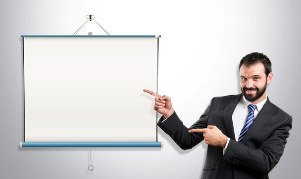Businessman pointing to projector screen over grey background - Photo, Image