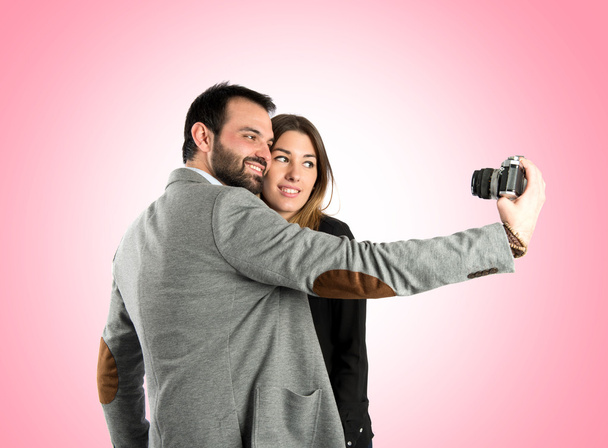 Man photographing with his girlfriend over pink background - Foto, afbeelding