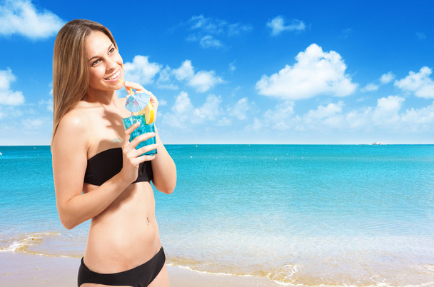 Woman drinking a cocktail on the beach - Photo, image