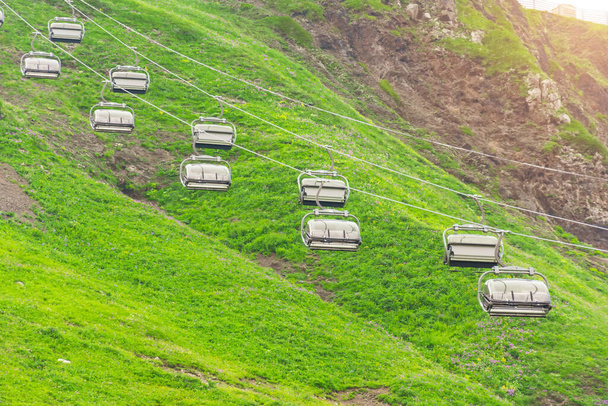 Trasa kolejki linowej w górach na zboczu szczytu latem z zieloną trawą - Zdjęcie, obraz