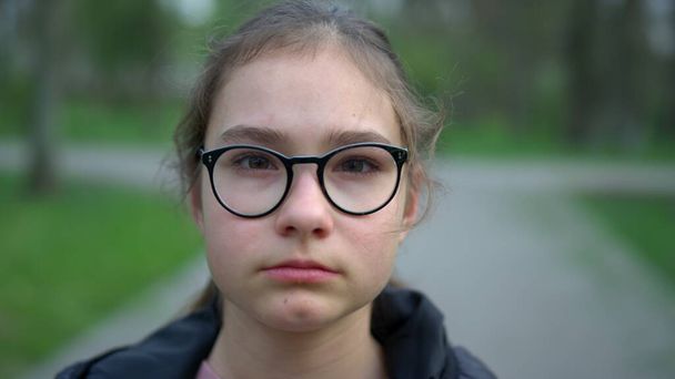 Portrait of serious girl staying in park. Teenager girl looking camera outdoors. - Photo, Image