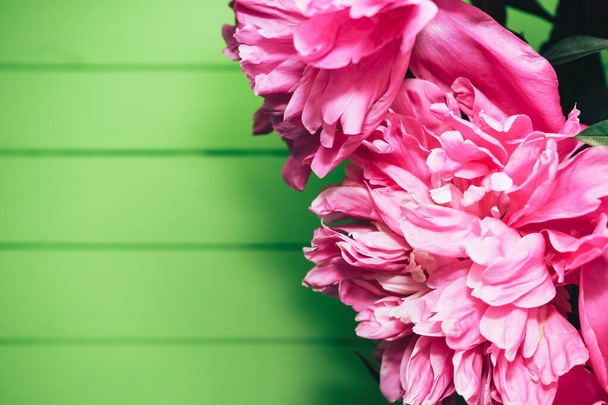 Закрыть Пион цветы в вазе на столе и зеленый деревянный фон стены. - Фото, изображение