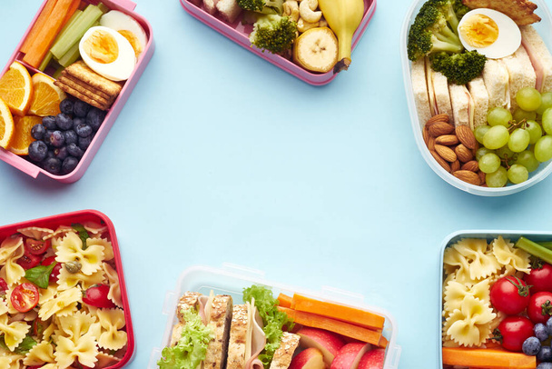 Top view pattern of school lunchboxes with various healthy nutritious meals on blue background - Photo, image