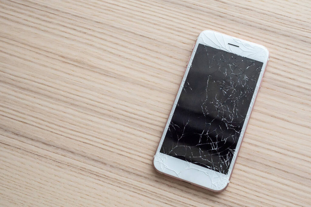 gebroken glas van mobiele telefoon scherm op houten achtergrond - Foto, afbeelding