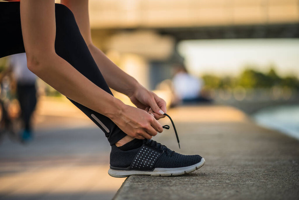 Young woman is tying a shoelace before jogging. - Photo, Image