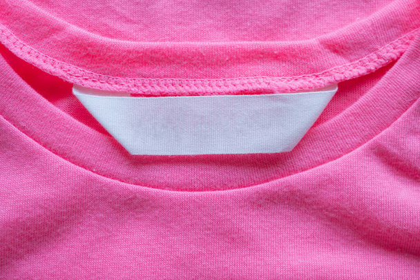 blanco wasgoed verzorgingskleding label op roze shirt - Foto, afbeelding