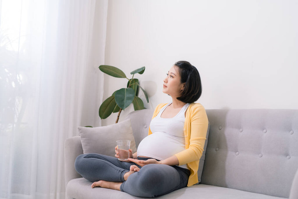 Βιταμίνες για εγκύους Προσδοκώμενη γυναίκα που κατέχουν δέσμη των χαπιών και ένα ποτήρι νερό - Φωτογραφία, εικόνα
