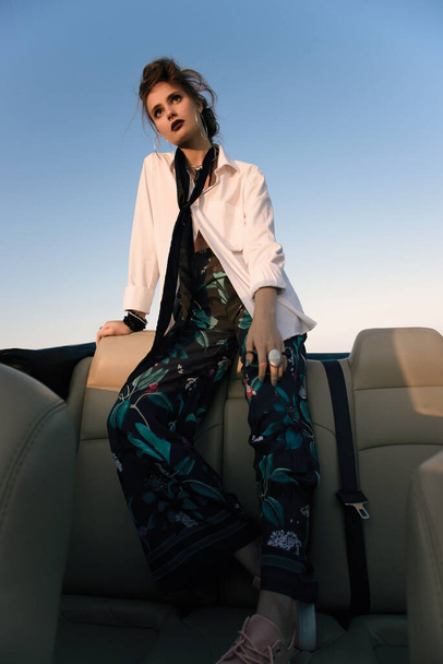 Joven chica elegantemente vestida en el asiento trasero de un convertible - Foto, Imagen