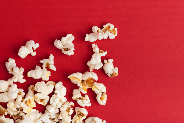 Popcorn on red Background. Snack when watching a movie. Flat lay with copy space. Cinema and entertainment concept. Template - Photo, Image