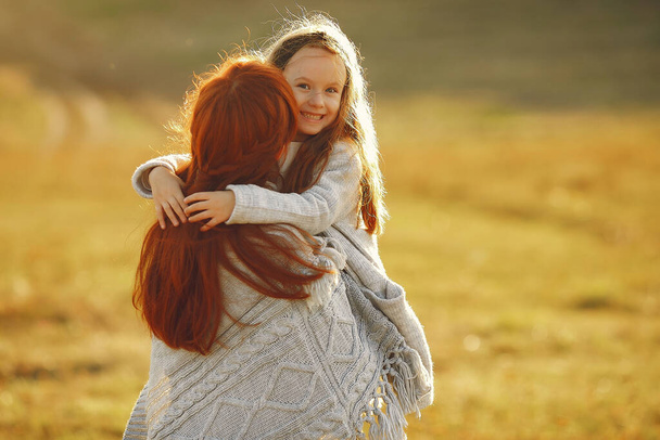 Mother with little daughter playing in a autumn field - Foto, afbeelding