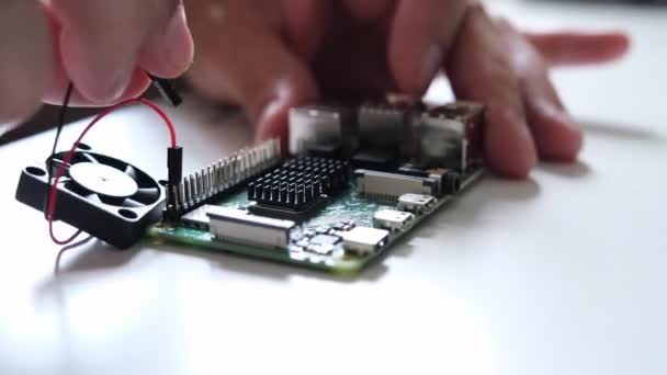 Primer plano de las manos masculinas conectando un pequeño ventilador a una computadora ARM de una sola placa. Concepto tecnológico.  - Metraje, vídeo