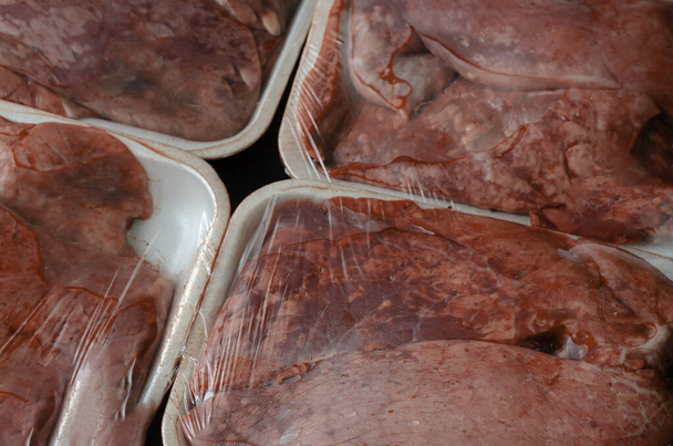Rauwe rundvlees longporties achtergrond. Slachtafval close-up. Witte dienbladen met vers vlees. Kopieerruimte. - Foto, afbeelding