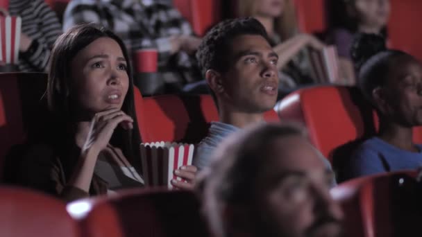 Coppie di razza mista guardando film spaventoso nel cinema - Filmati, video