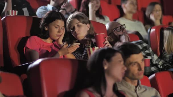 Teen girls using smartphone während film im kino - Filmmaterial, Video