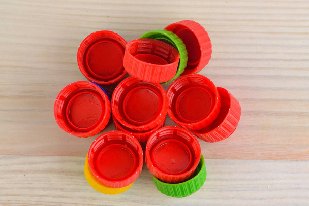 Multicolored plastic caps on wooden background - Photo, Image