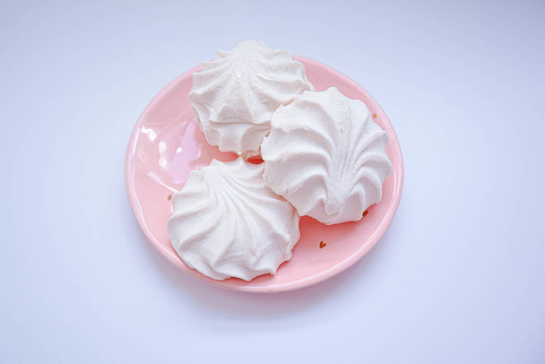 Білий солодкий зефір лежить на керамічній рожевій тарілці. З вільним простором для тексту. Крупним планом солодощі
. - Фото, зображення