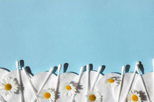 Ear sticks, white cotton pads and romomiles on a blue background with copy space. Концепция гигиены и личной гигиены тела. - Фото, изображение