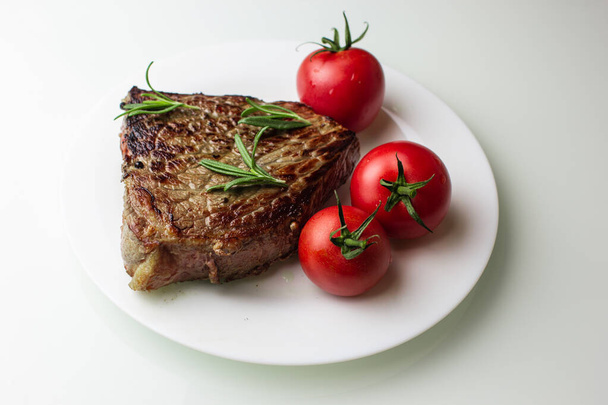 Biberiye ve biberiyeyle tatlandırılmış, beyaz tabakta sebzeli ızgara biftek. - Fotoğraf, Görsel