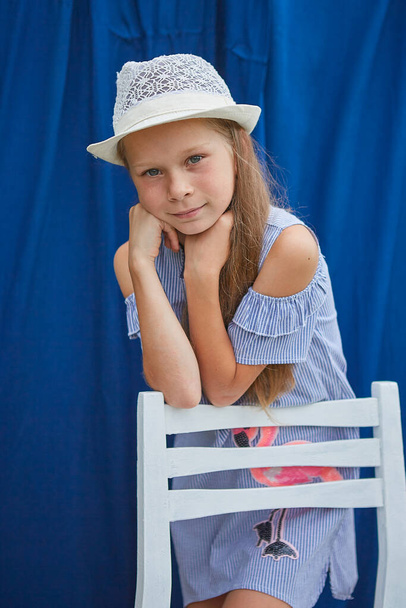 Little girl with hat, on a blue background, outside - Фото, изображение