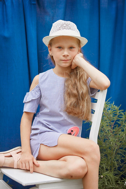 Little girl with hat, on a blue background, outside - Foto, afbeelding