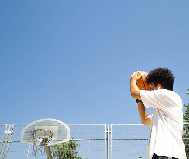An afro teenage boy with ball in basketball court - Zdjęcie, obraz
