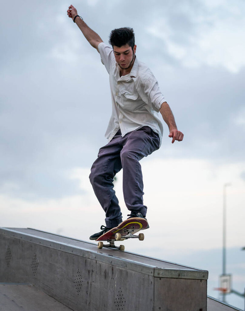 A vertical shot of a European male jumping on a skateboard in a skate park - Фото, изображение