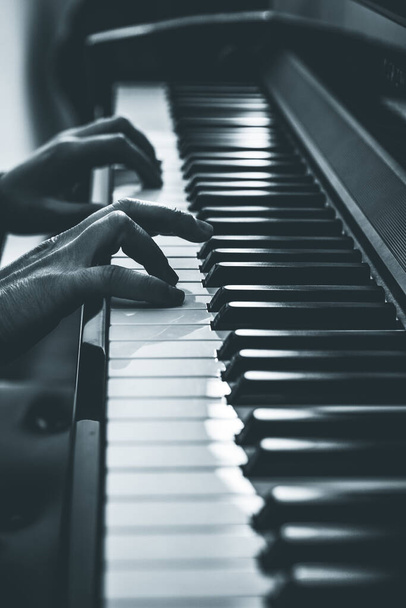 A vertical grayscale shot of a male playing the piano - Foto, Bild
