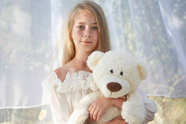Little girl in white chiffon tent with toy. Childhood, tenderness, beauty - Фото, изображение