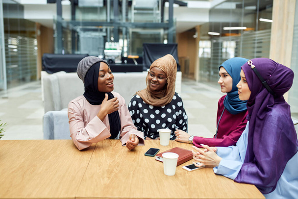 Kuva onnellinen muslimi monikansallinen tytöt opiskelijat keskustelevat kirjan kirjastossa. - Valokuva, kuva