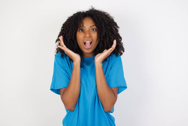 Überraschte verängstigte junge Afrikanerin mit lockigem Haar in lässigem blauem Hemd vor weißem Hintergrund Gesten mit Unsicherheit, starrt in die Kamera, verwirrt, als wüsste sie keine Antwort auf knifflige Frage Menschen, Körpersprache, Emotionskonzept - Foto, Bild