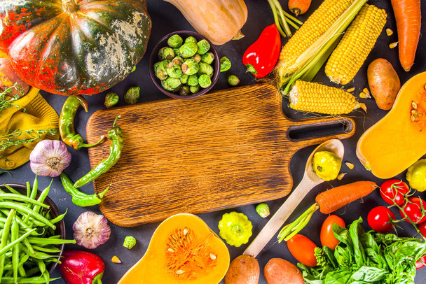 Herfst kookachtergrond. Biologische herfstoogst groenten, rauwe veganistische ingrediënten voor het koken van traditionele Thanksgiving en herfst voedsel op donkere achtergrond, bovenaanzicht  - Foto, afbeelding