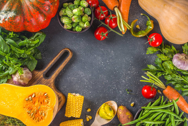 Autumn cooking background. Organic autumn harvest vegetables, raw vegan ingredients for cooking traditional thanksgiving and fall food on dark background, top view  - Photo, Image