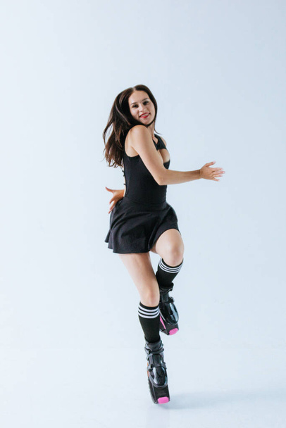 Beautiful fit caucasian woman jumps in shoes for kangoo jumping on white background - Photo, Image