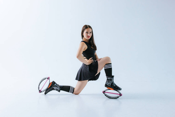 Beautiful fit caucasian woman posing in shoes for kangoo jumping on white background - Foto, immagini