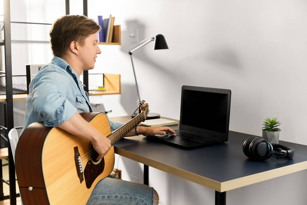 young man with laptop and guitar at home - 写真・画像