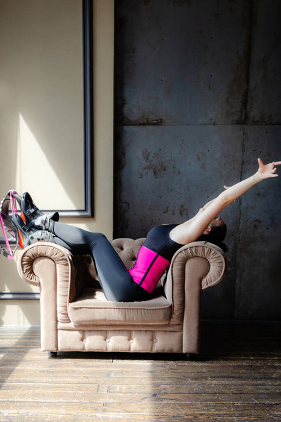 Beautiful fit caucasian woman posing in shoes for kangoo jumping sitting on armchair - Foto, Bild