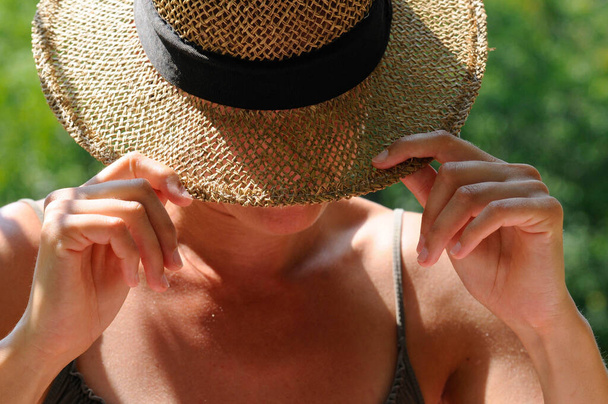 femme portant un chapeau de paille pour la protection solaire, fond vert flou - Photo, image