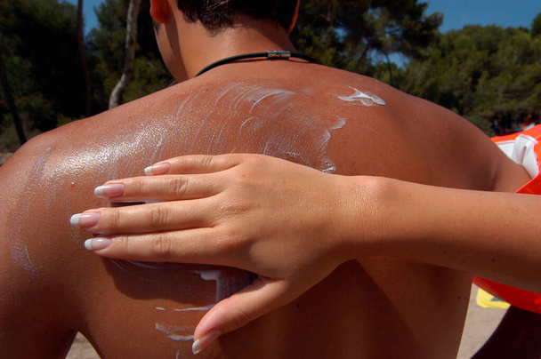 záda muže se třou s opalovacím krémem, ochrana kůže v horkém letním dni - Fotografie, Obrázek