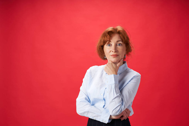 Beautiful redhead woman posing on red background - Fotoğraf, Görsel