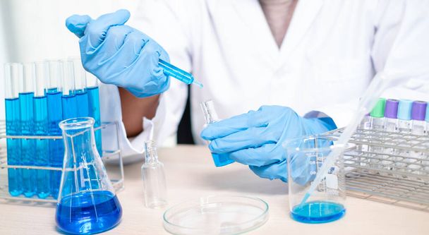 Tıp bilimcileri bir kimya laboratuvarında virüsü analiz etmek için deney şişesine yerleştirilmiş bir örnek bıraktılar. Bilimsel araştırma kavramları. - Fotoğraf, Görsel