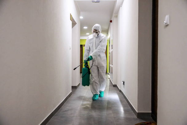Travailleur en costume stérile et masque salle de stérilisation d'un bâtiment du virus corona / covide 19. - Photo, image
